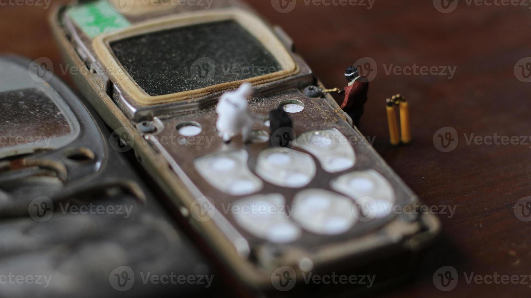 miniature figure of a technician repairing an old broken cell phone. working technician concept. photo