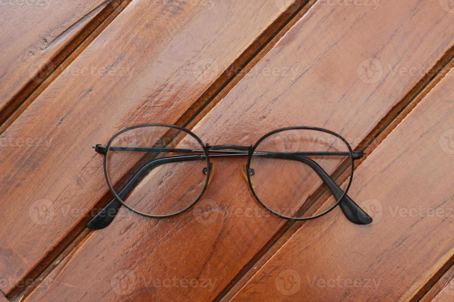 a close up of eyeglasses with black frames isolated natural patterned wooden background. photo