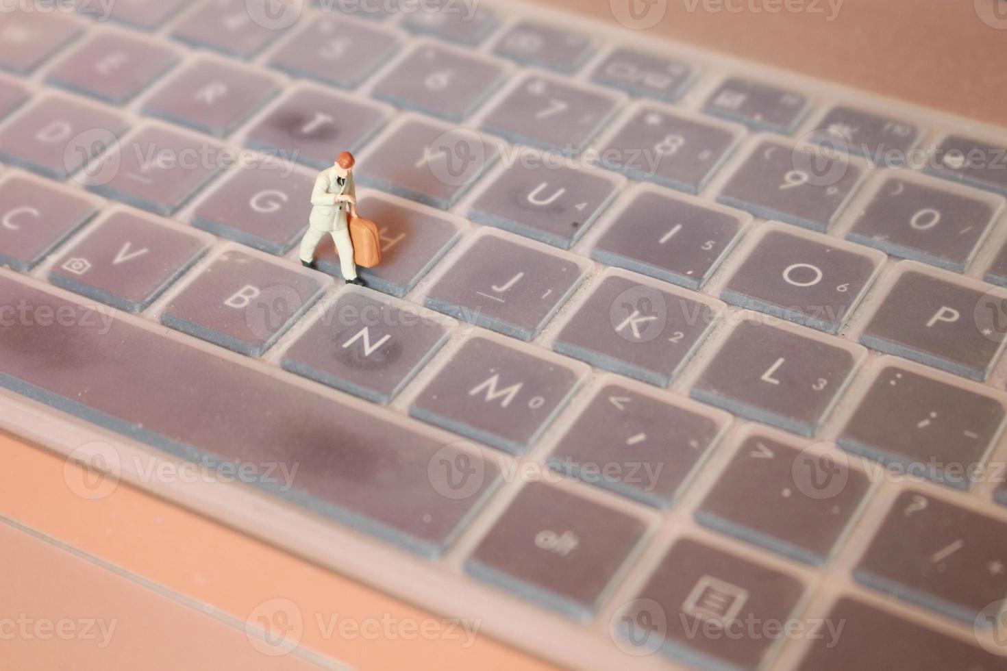 a miniature figure of an office worker carrying a briefcase walking between the keyboards. photo