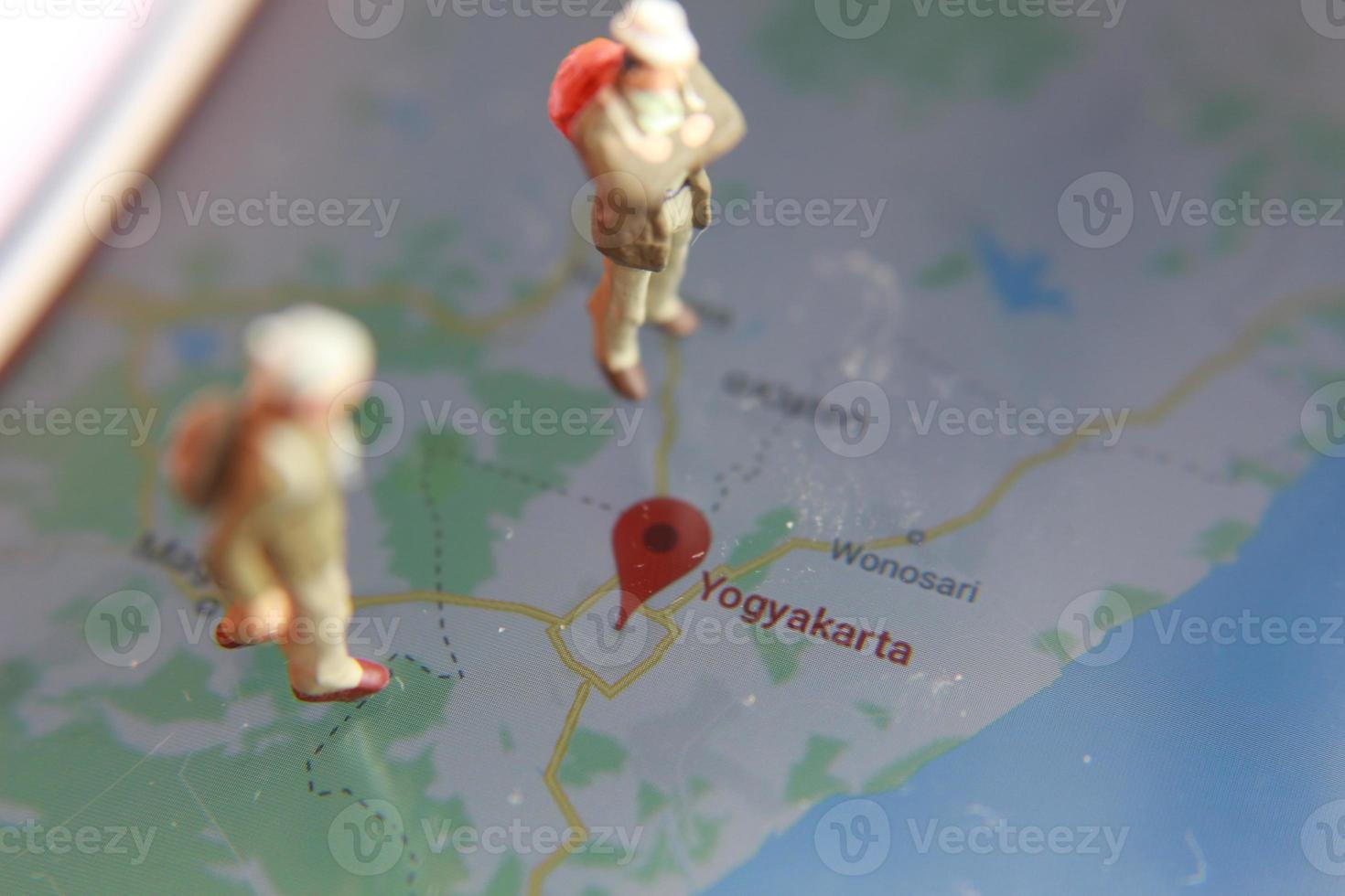 miniature figure of an explorer posing on a digital map via a mobile phone photo