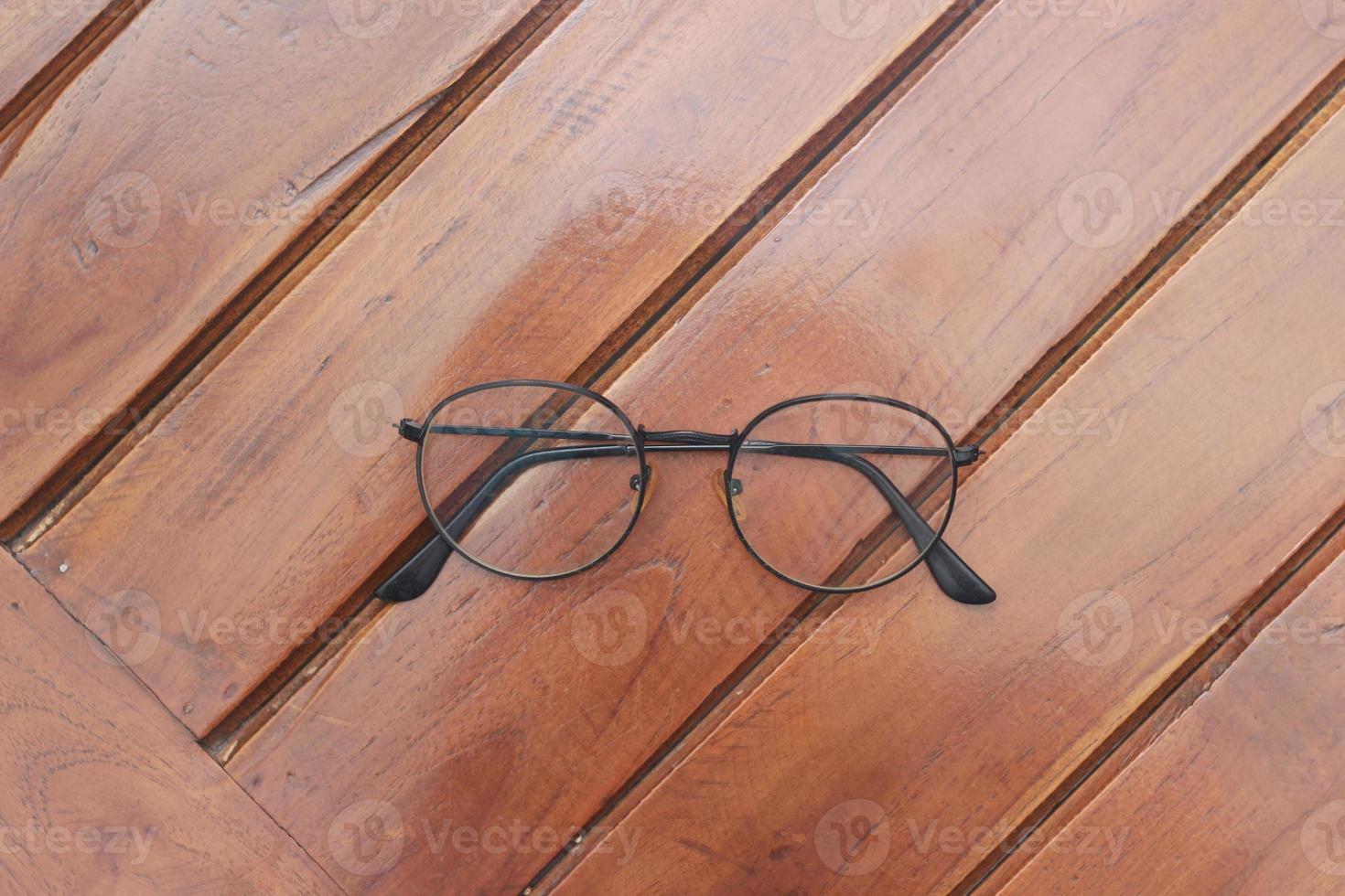 a close up of eyeglasses with black frames isolated natural patterned wooden background. photo