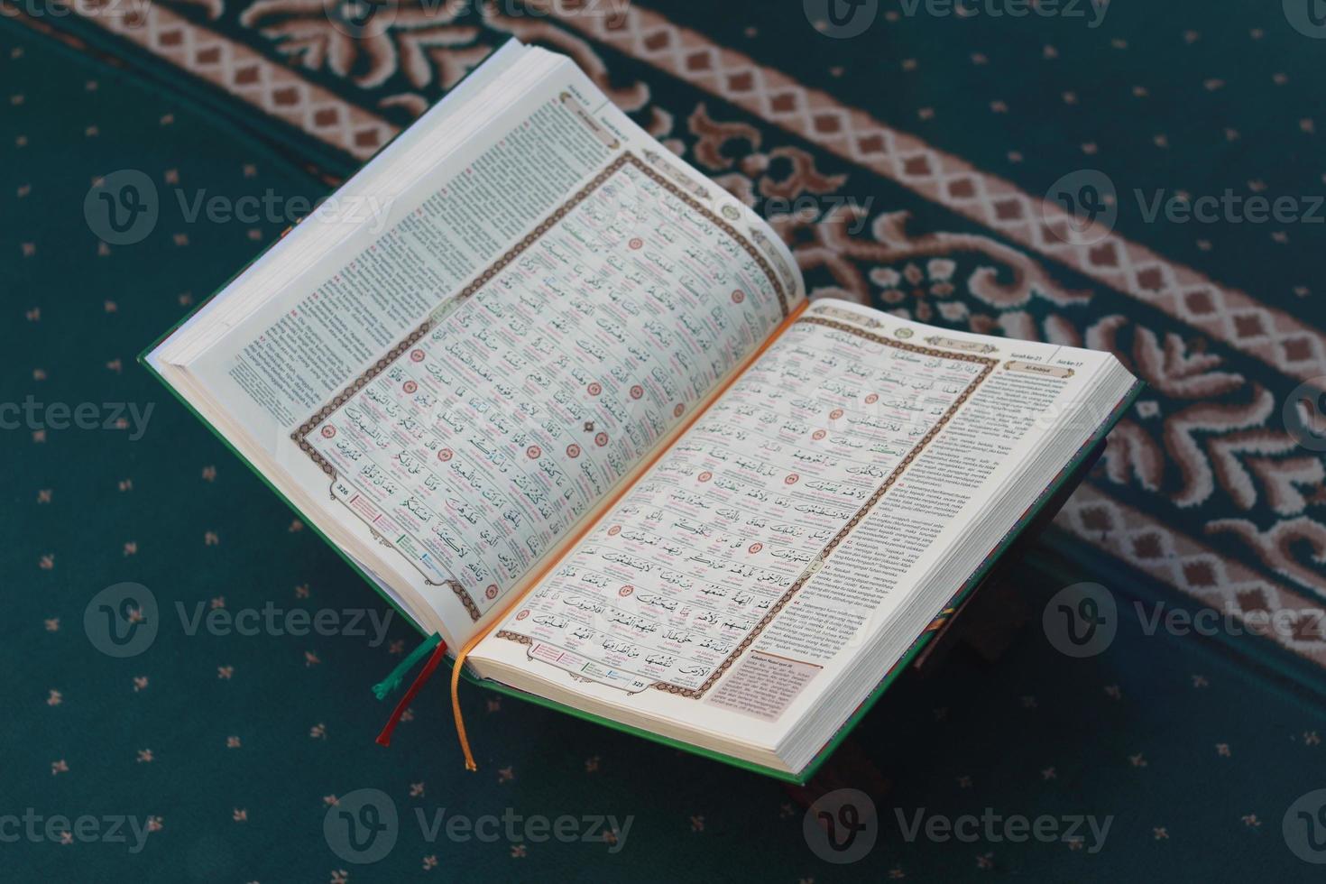 a close up of the holy book Al-Quran on a green prayer rug. Islamic photo concept.