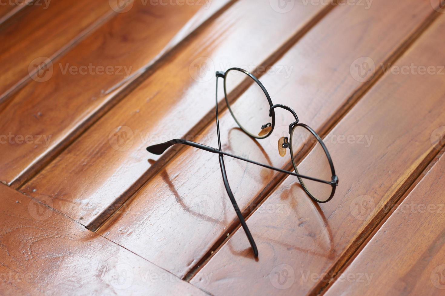 a close up of eyeglasses with black frames isolated natural patterned wooden background. photo