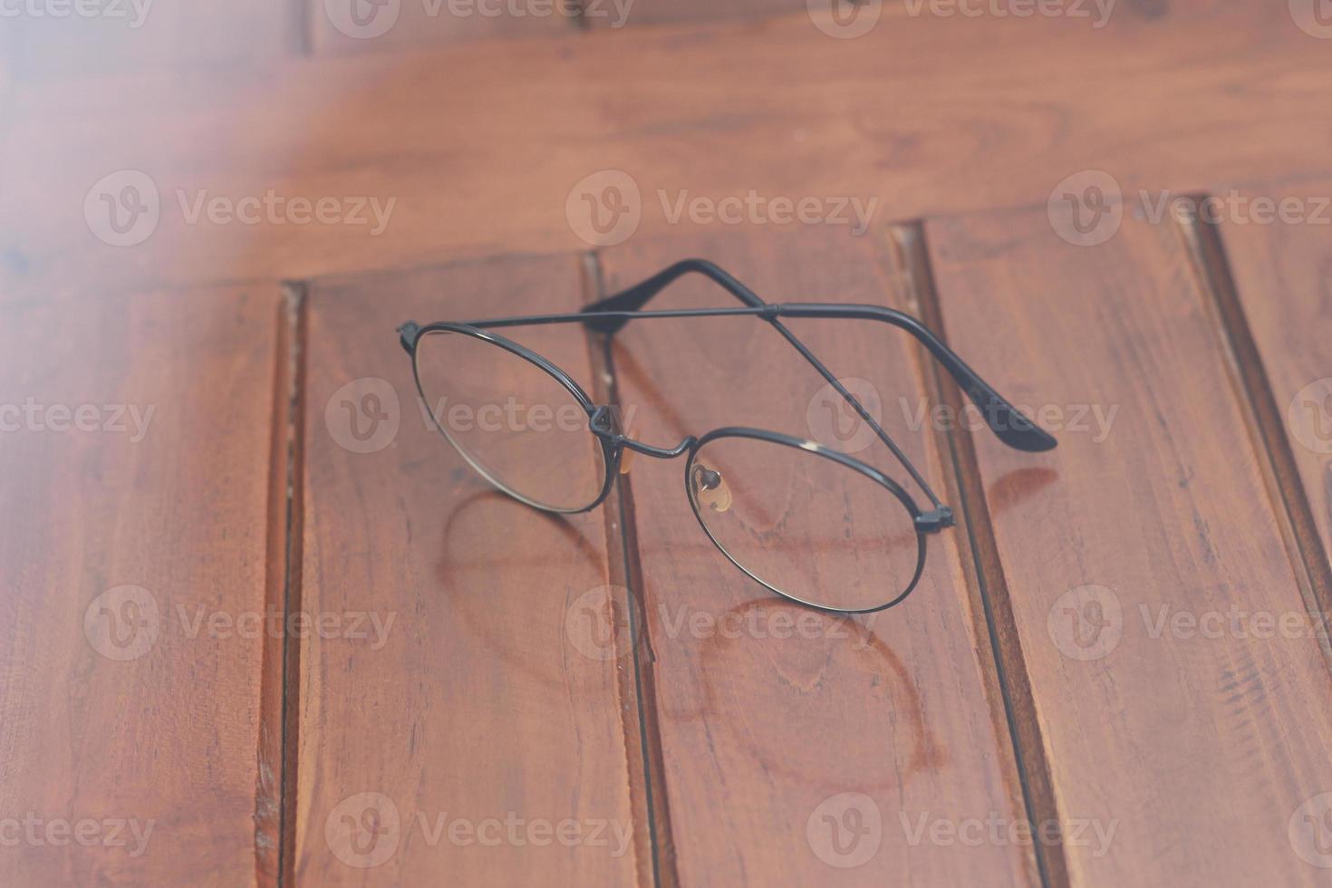 a close up of eyeglasses with black frames isolated natural patterned wooden background. photo