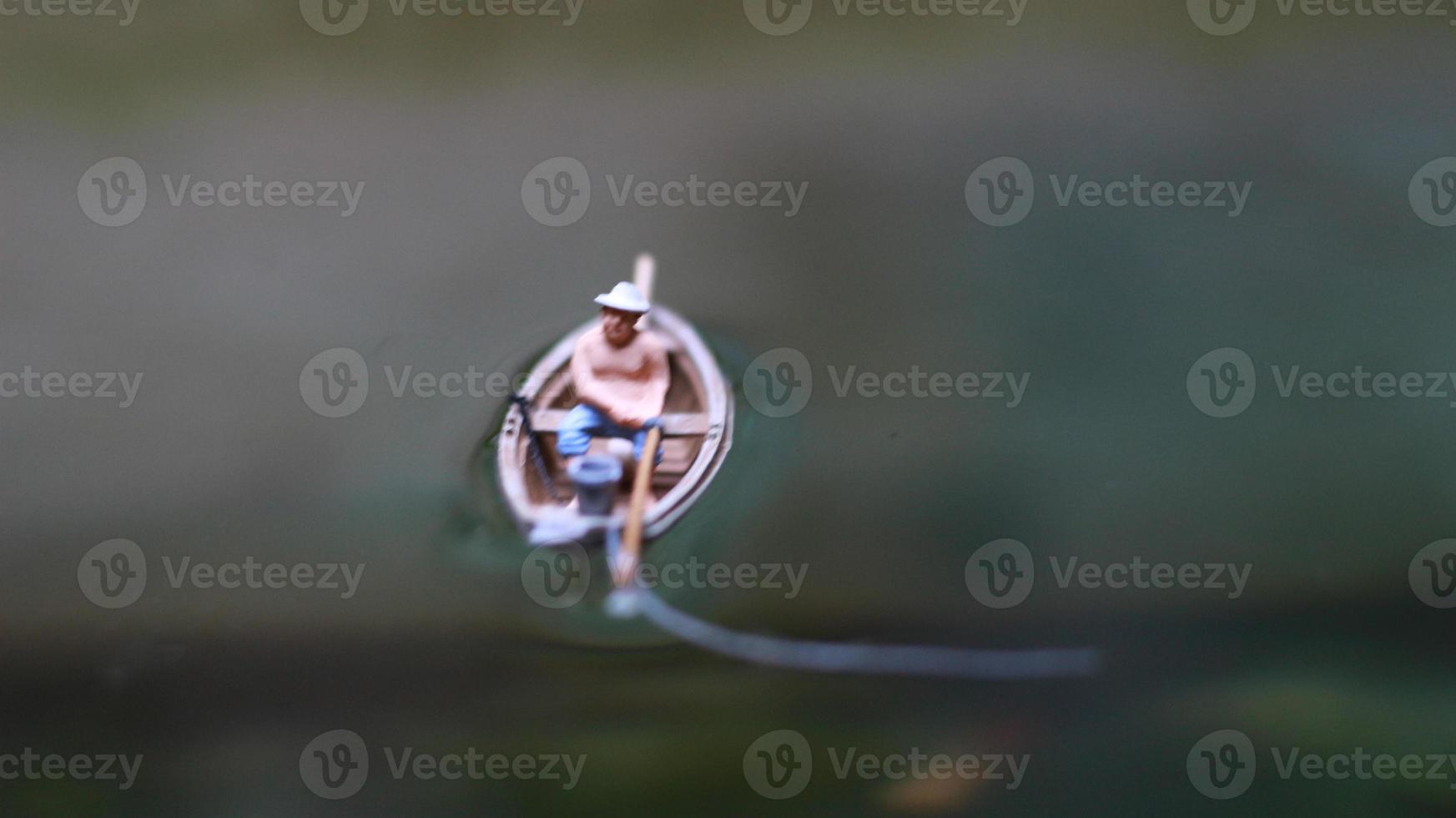 miniature figure of a fisherman fishing on a lake in a small boat. photo