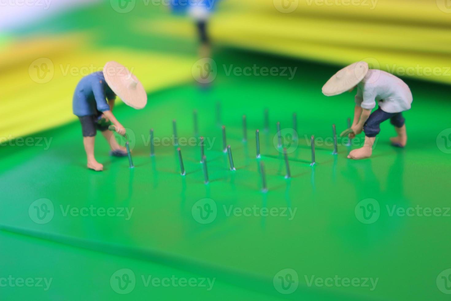 miniature figure of farmers growing crops in the form of staples on green paper. Concept of agriculture photo. photo