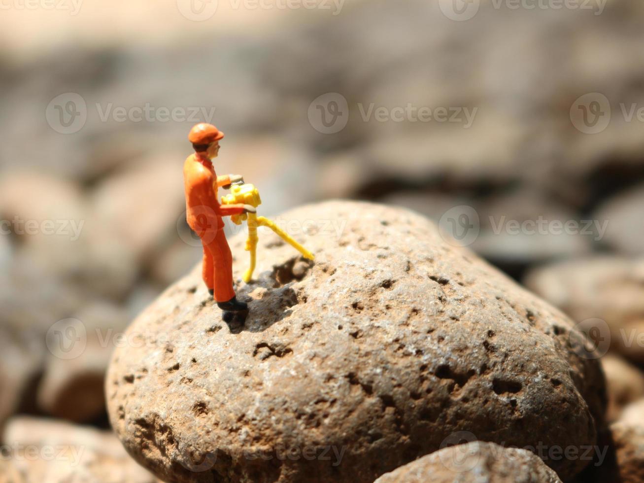 a close up of miniature figures of miners crushing rock. Mining photo concept.