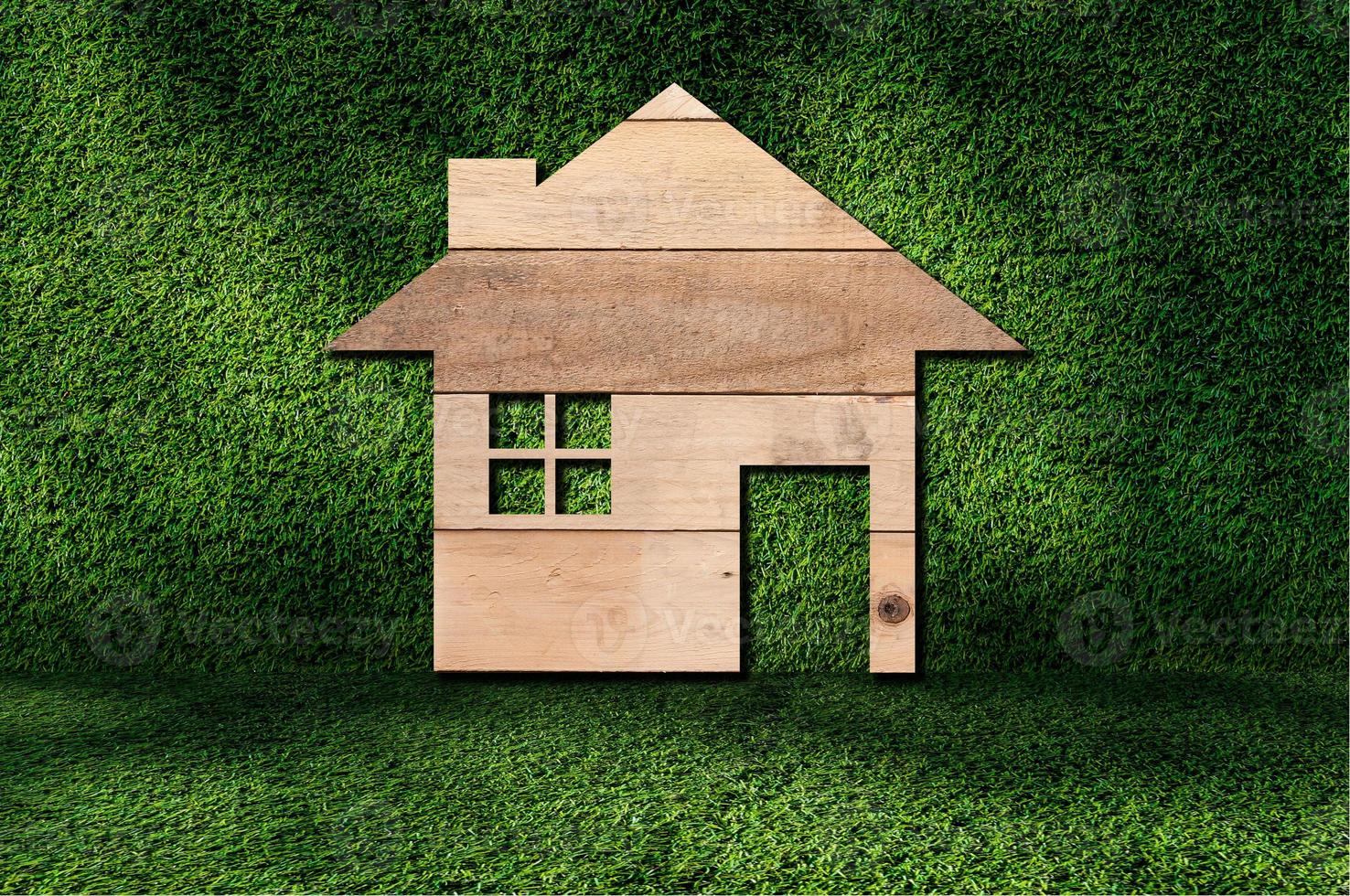 house icon from wooden texture on grass background photo