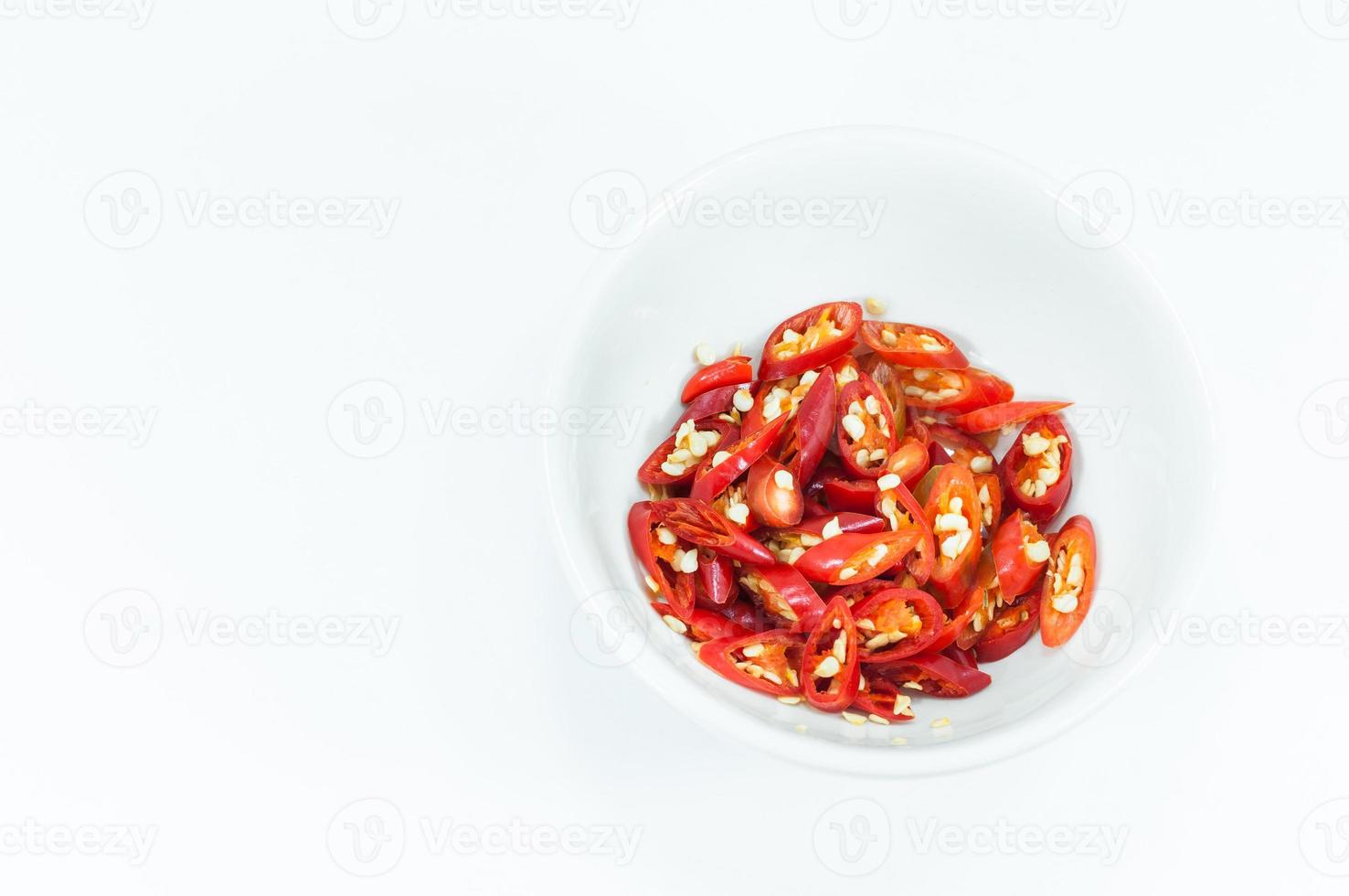 Cortado y rebanadas de rojo chile en un blanco taza aislado en blanco fondo, arriba ver foto