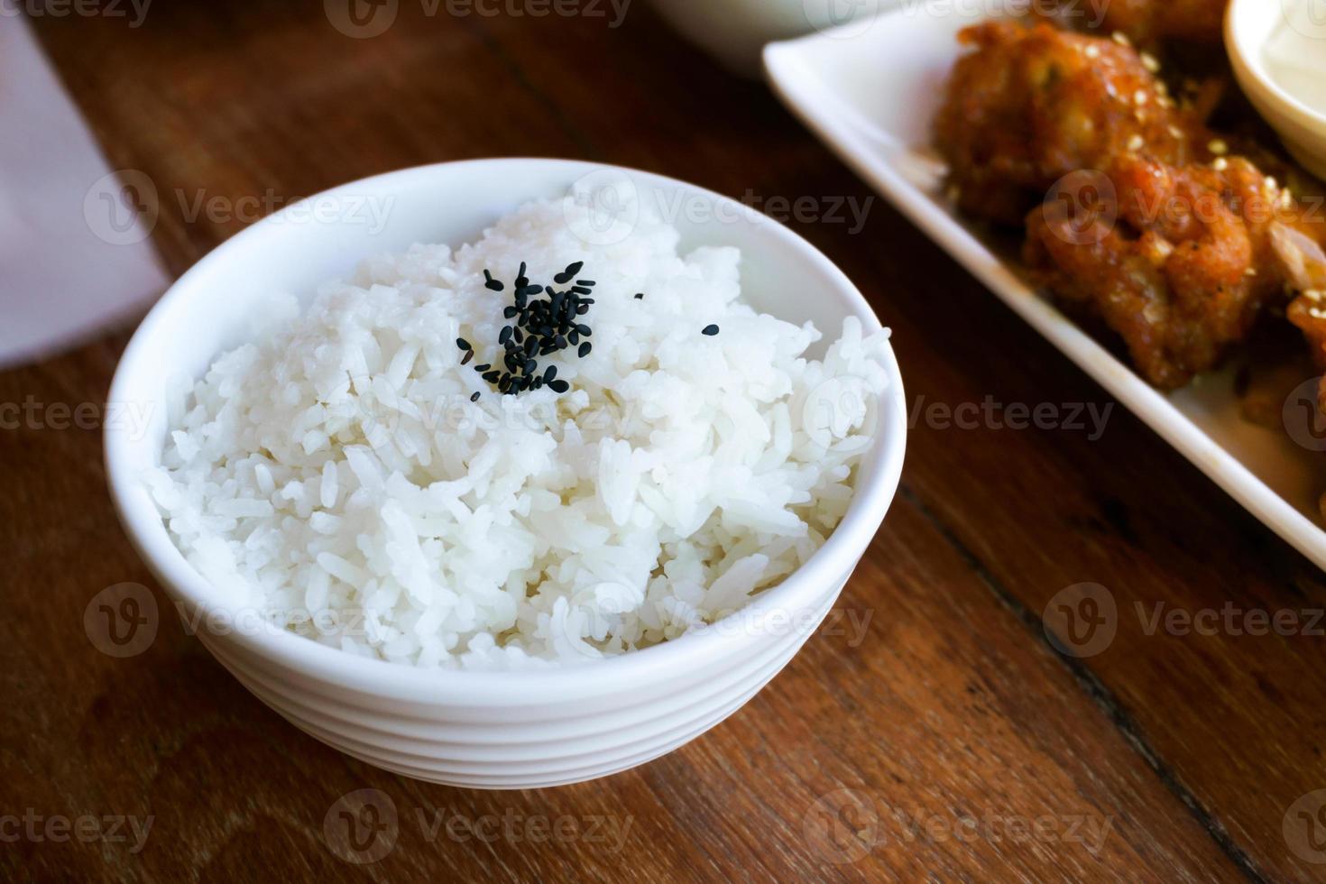 Rice in white cup on wood background and black sesame photo