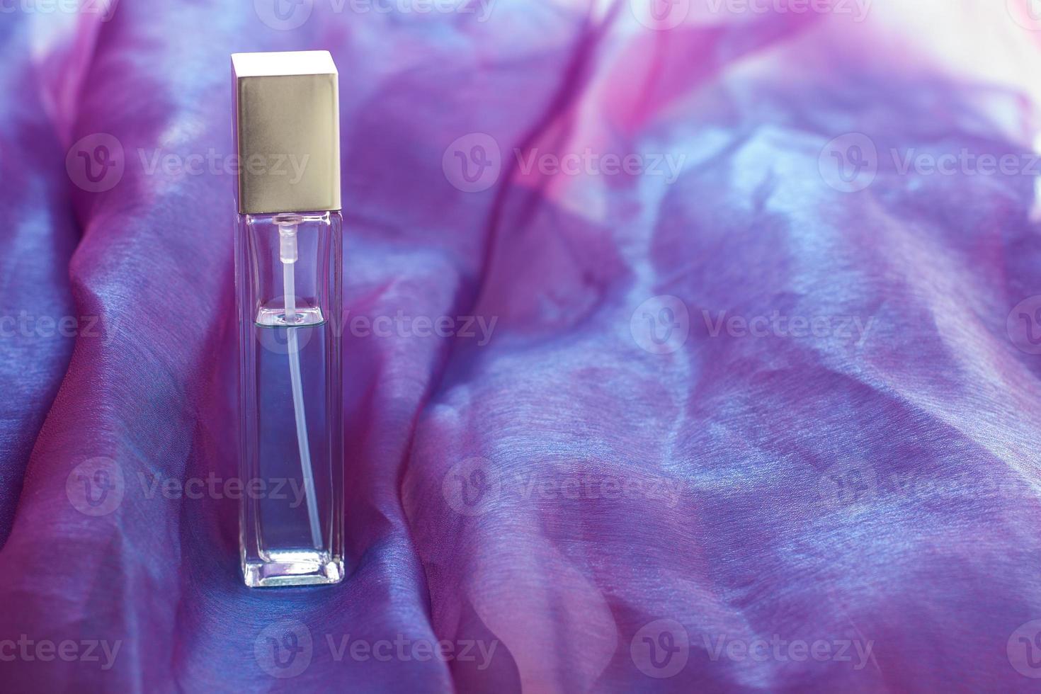 A long bottle of liquid stands on a pink cloth. Glass elongated faceted vial. Blank for mock up with copy space. Horizontal. photo