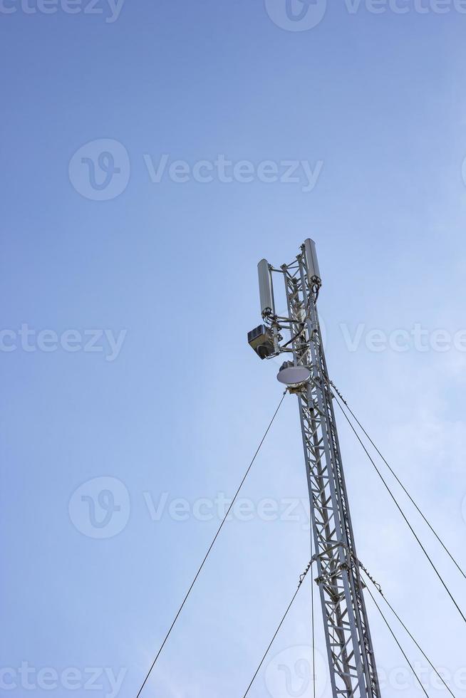 Antenna cellular tower and blue sky. Vertical view photo