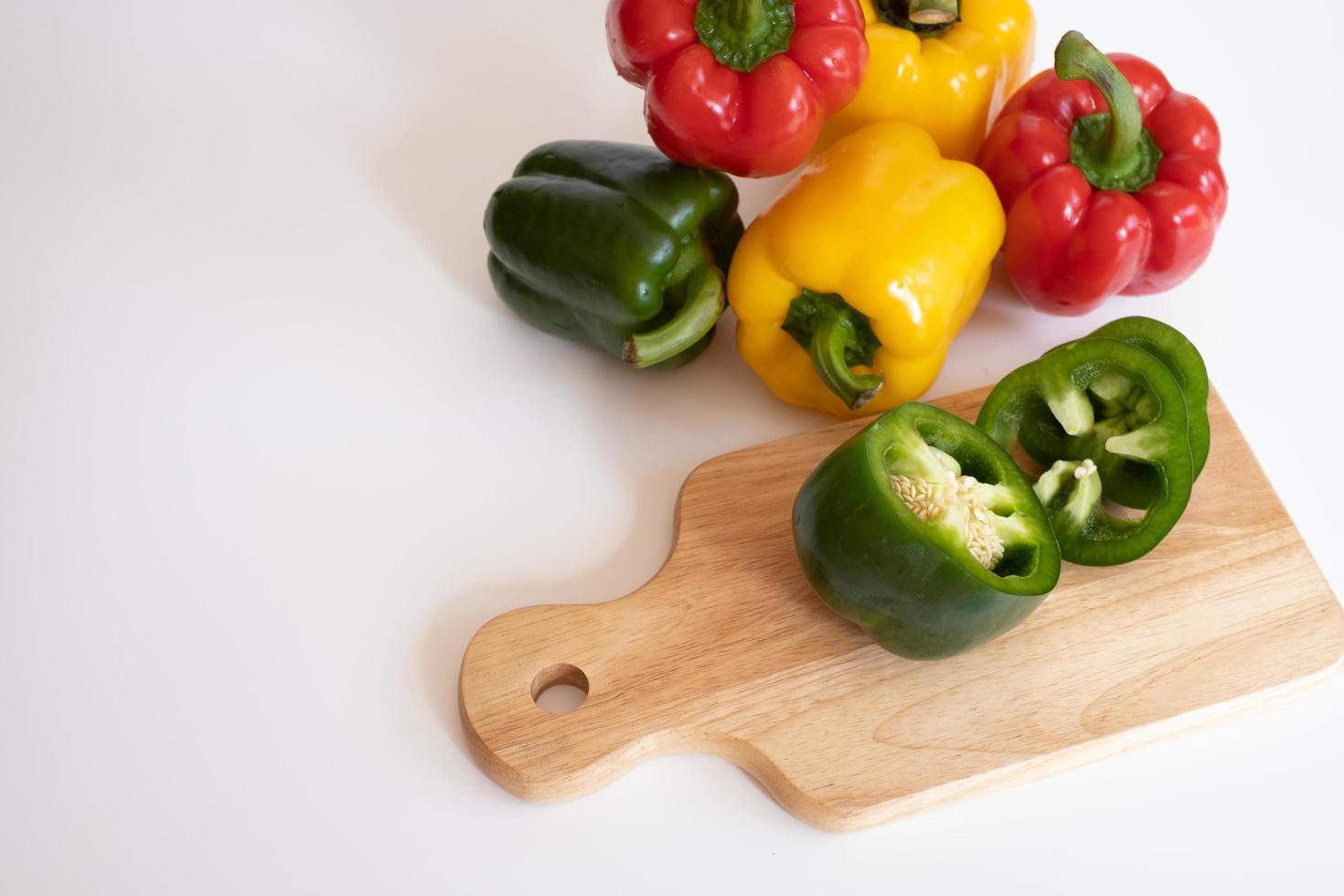 Top view of cutting sweet bell pepper on the wooden board isolated on white background. photo