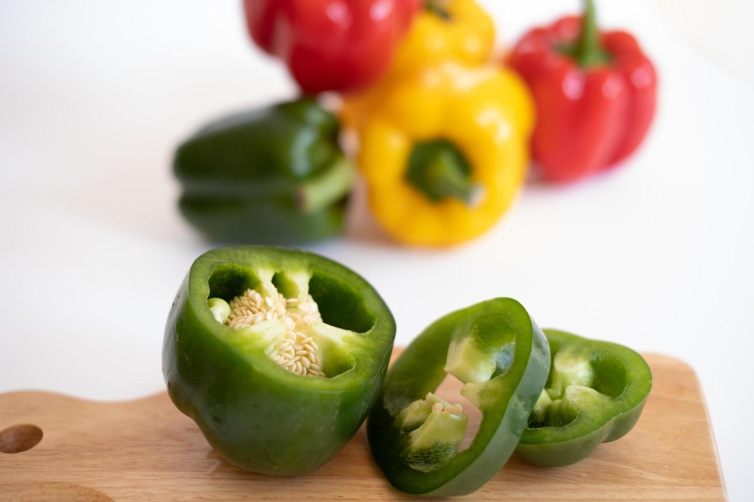 Top view of cutting sweet bell pepper on the wooden board isolated on white background. photo