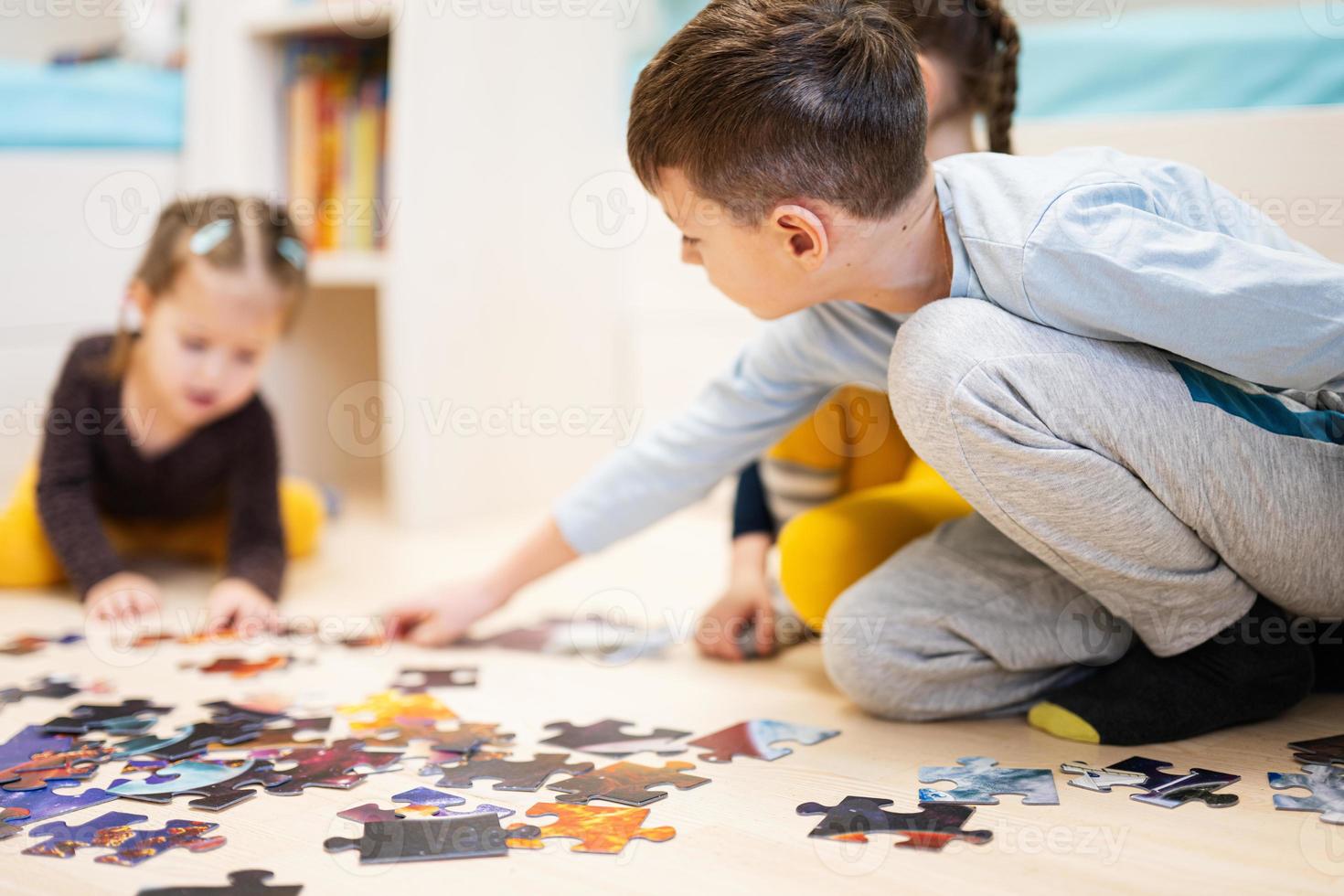 Children connecting jigsaw puzzle pieces in a kids room on floor at home.  Fun family activity leisure. photo