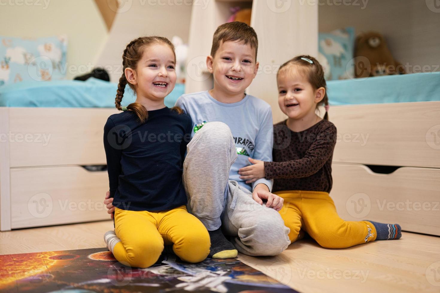 niños conectando piezas de rompecabezas en una habitación para niños en el piso en casa. diversión actividad familiar ocio. foto