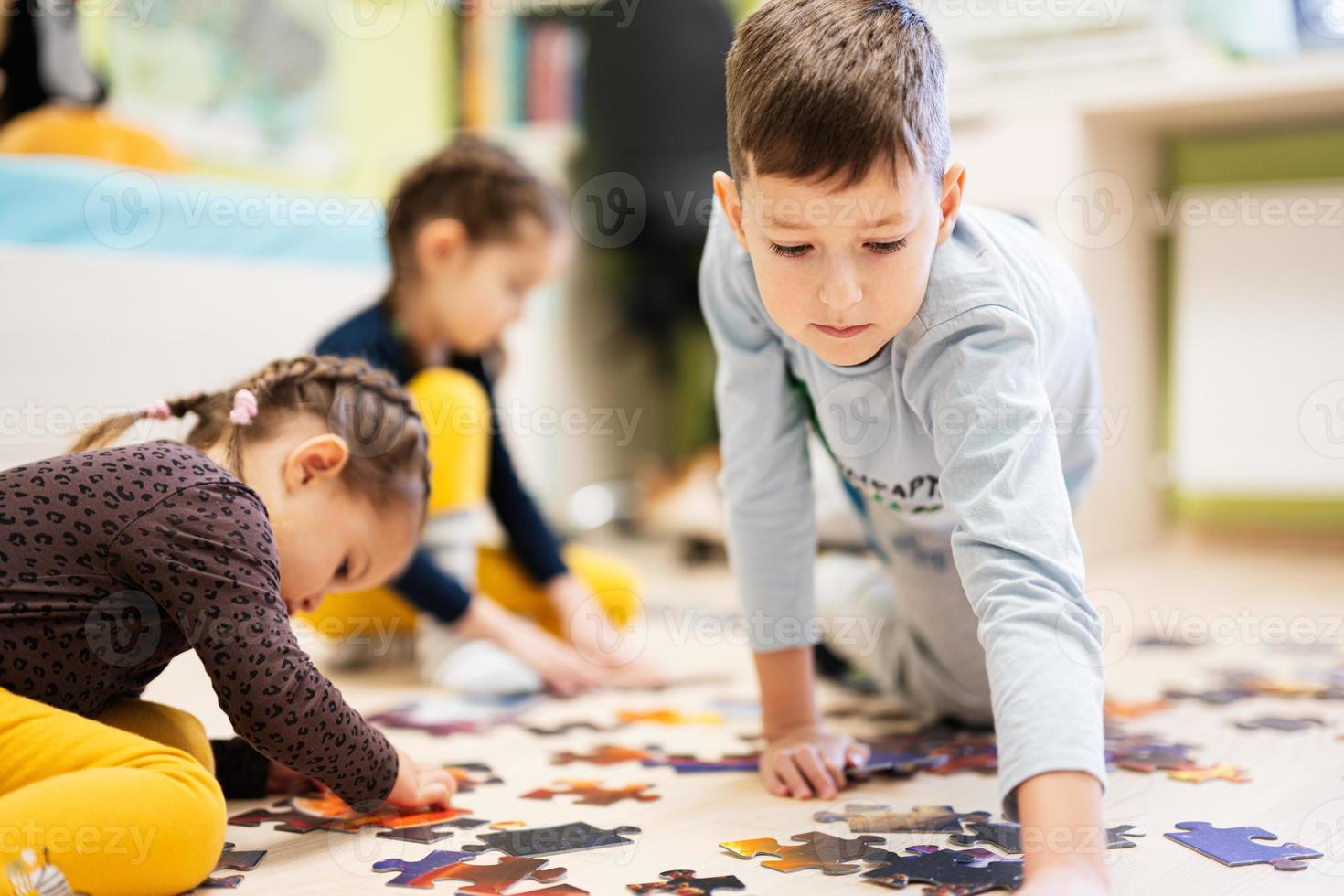 Children connecting jigsaw puzzle pieces in a kids room on floor at home.  Fun family activity leisure. photo