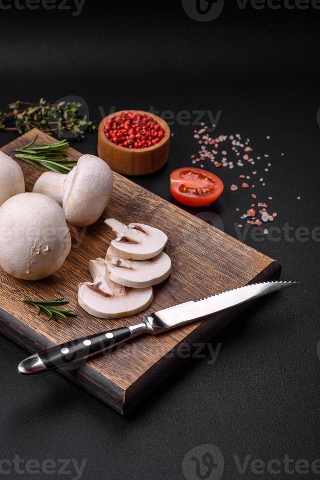 Fresh raw champignon mushrooms on a wooden cutting board with spices photo