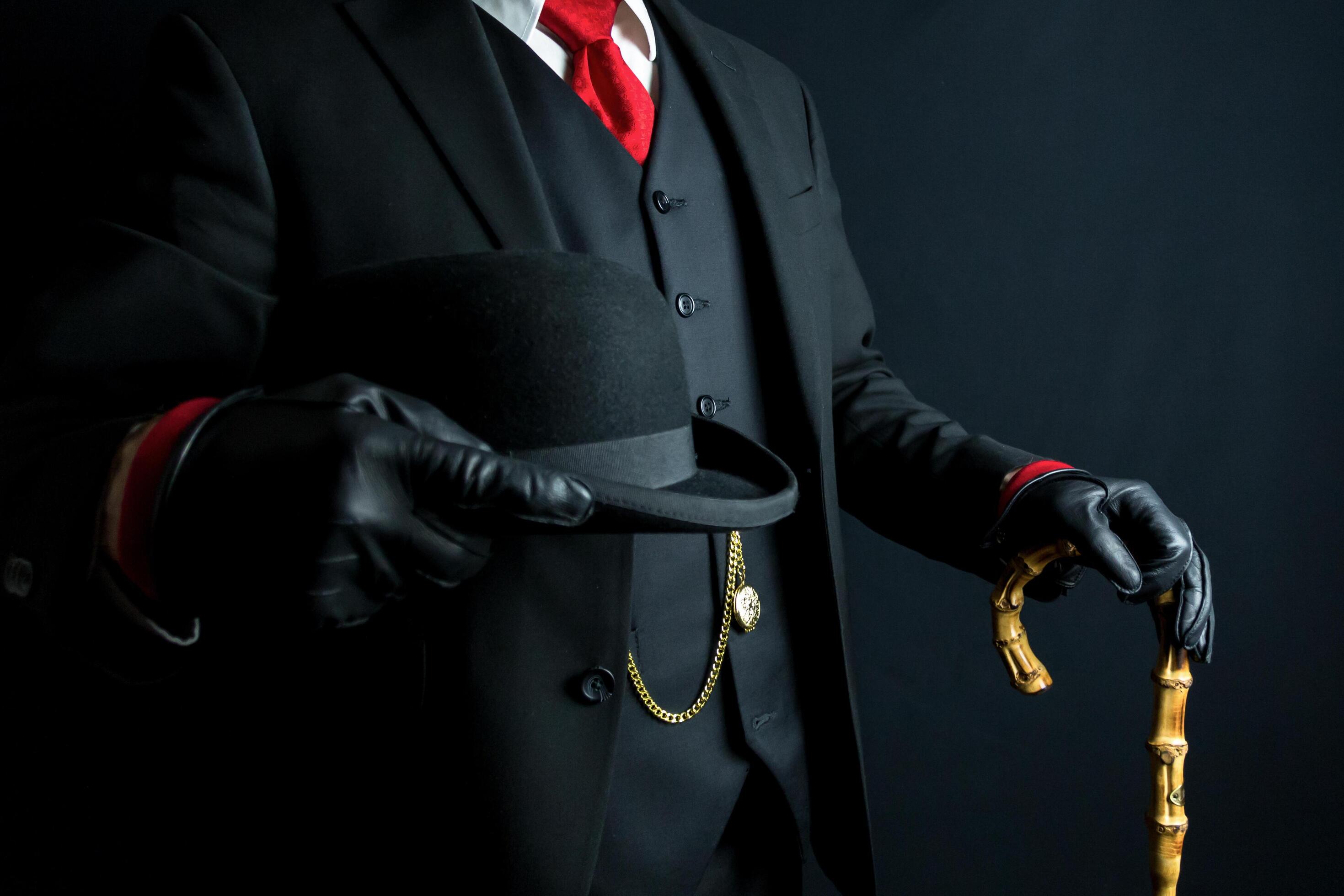 Man in Dark Suit and Leather Gloves Holding Umbrella and Bowler Hat