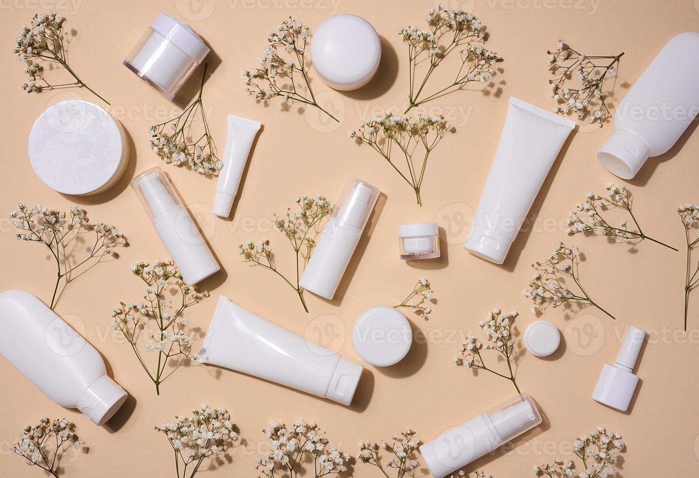 blanco el plastico tubos, frascos, y Gypsophila ramas en un beige fondo, contenedores para cosmético cremas y geles, publicidad y marca promoción, parte superior ver foto