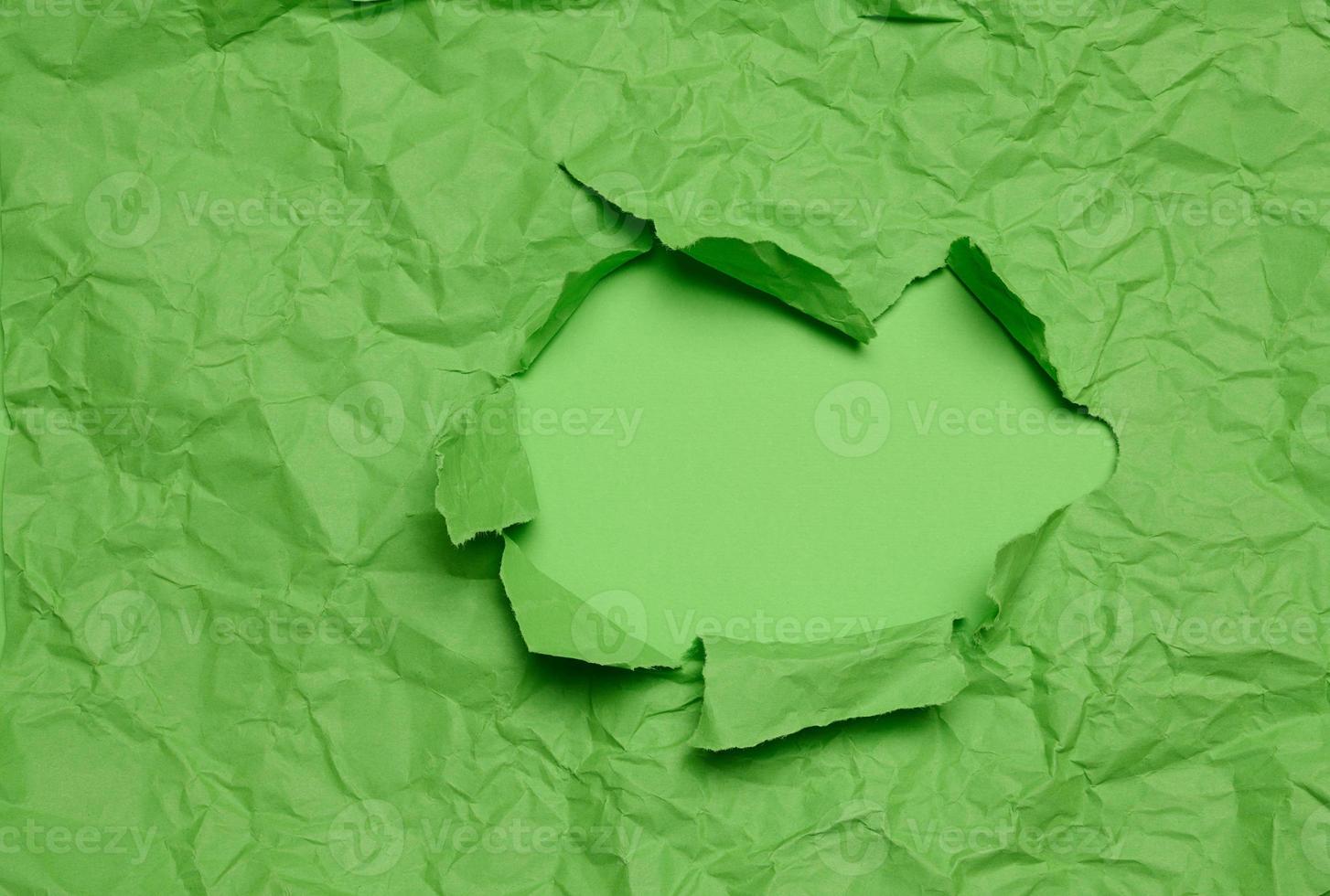 Texture of crumpled green paper with torn hole and green background, template for designer photo