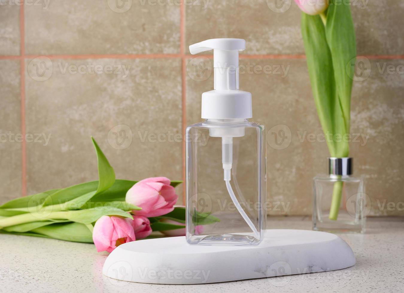 Transparent plastic container with a dispenser on the table. Bottle for liquid soap, shampoo photo