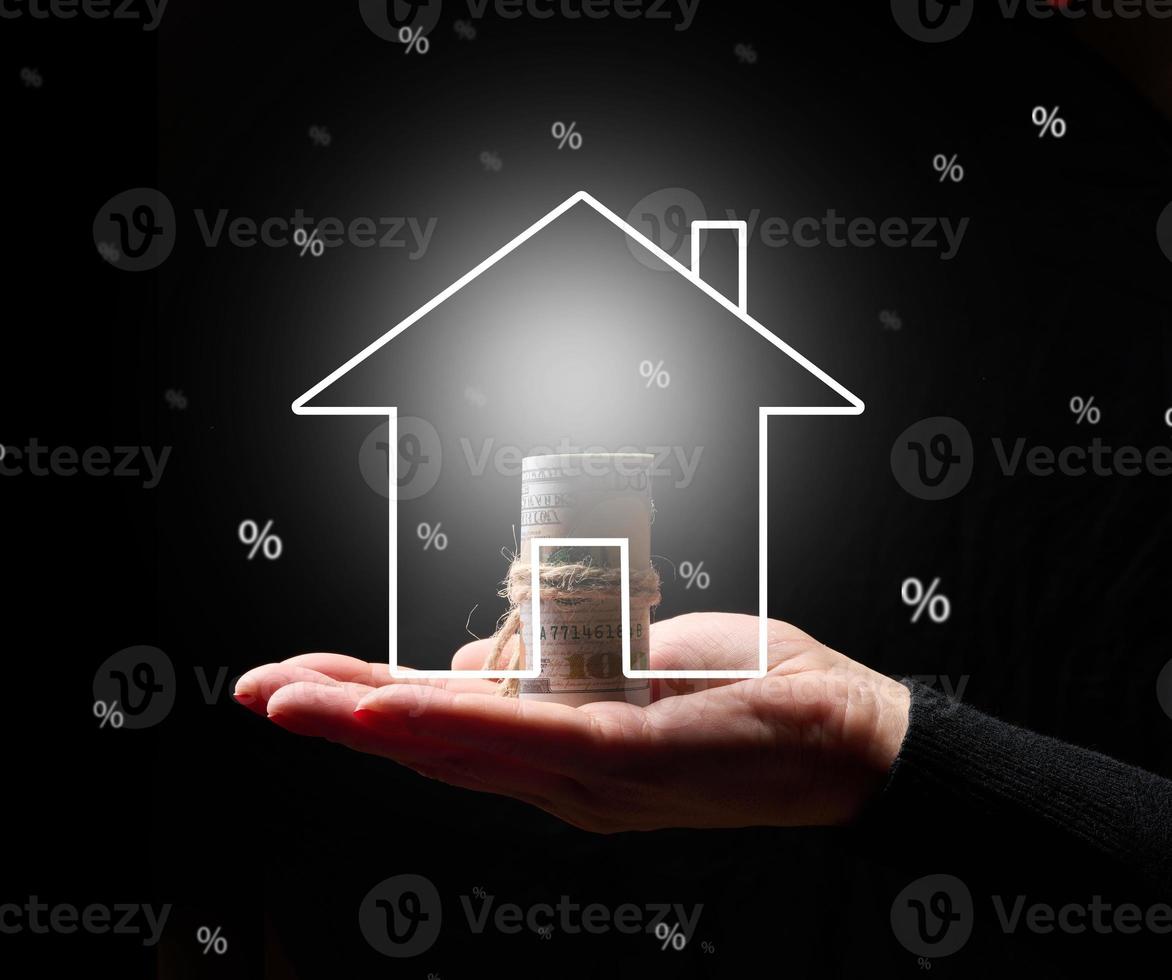 Hand holding virtual house neon icon on a black background. Real estate insurance concept, rent and mortgage photo