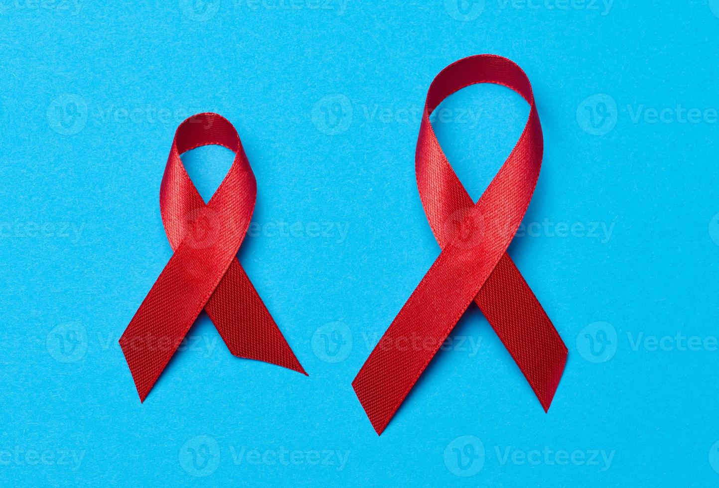 un seda rojo cinta en el formar de un arco en un azul fondo, un símbolo de el lucha en contra SIDA y un firmar de solidaridad y apoyo foto