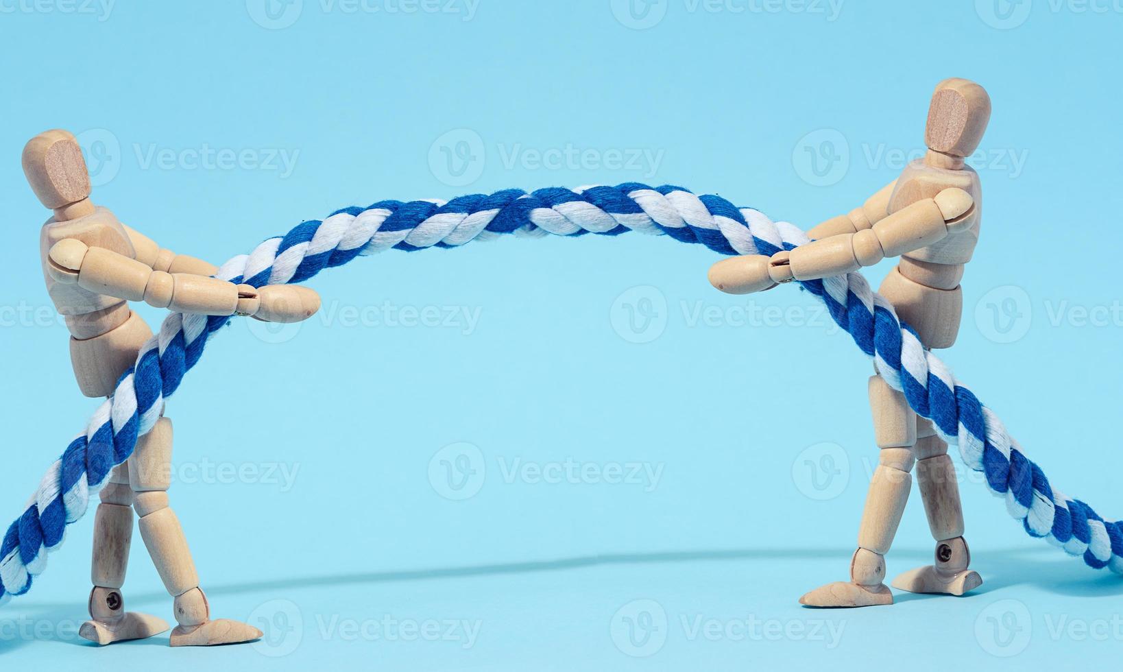 Two wooden mannequins are pulling a rope, concept of a strong leader in business photo