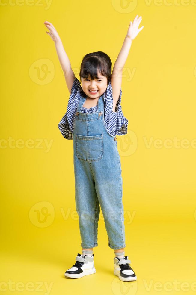 full body image of beautiful asian baby girl on yellow background photo