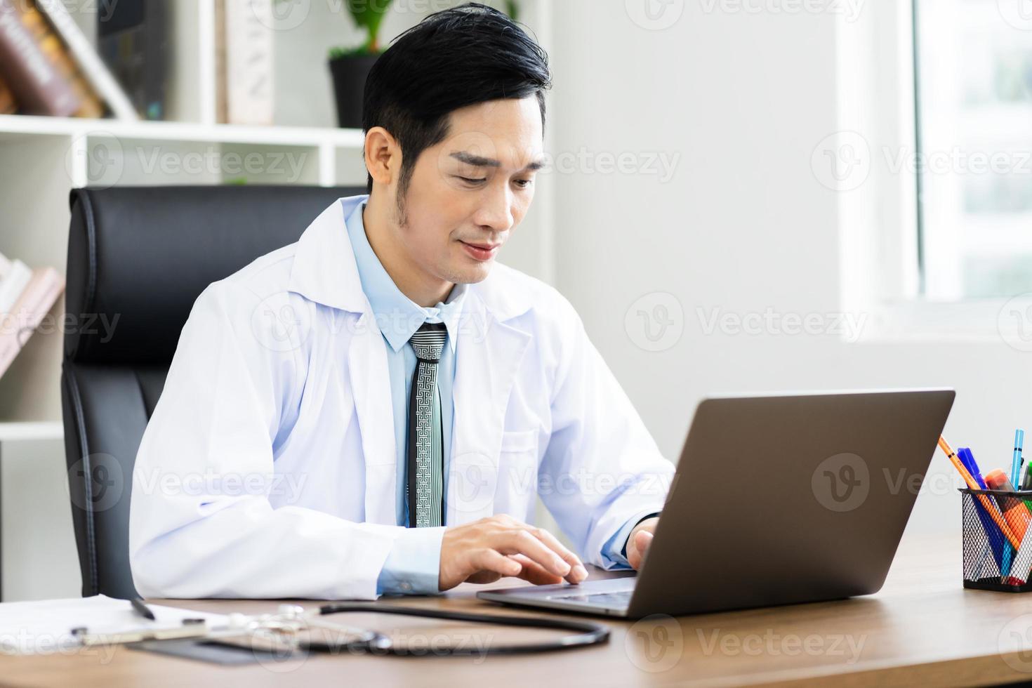 Asian male doctor portrait sitting at work photo