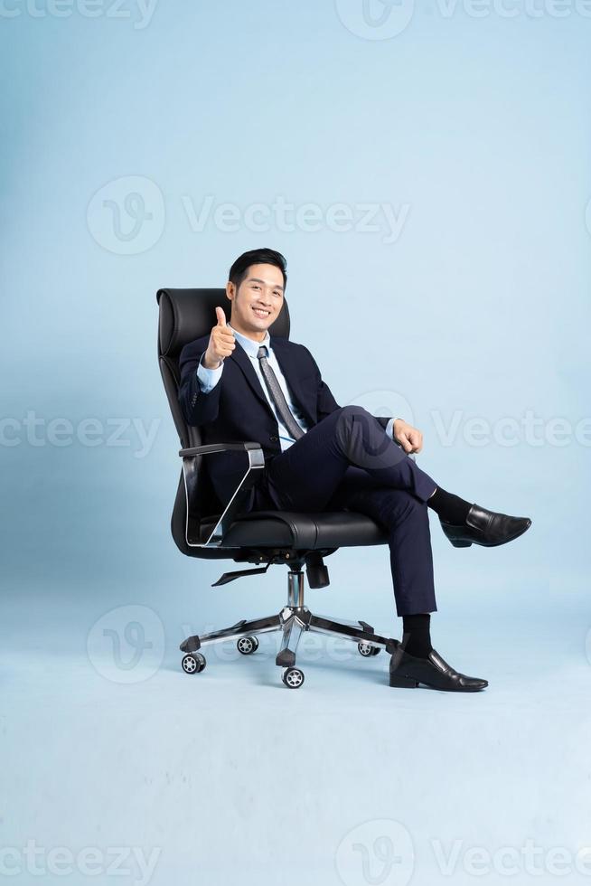 Asian businessman male portrait sitting on chair and isolated on blue background photo