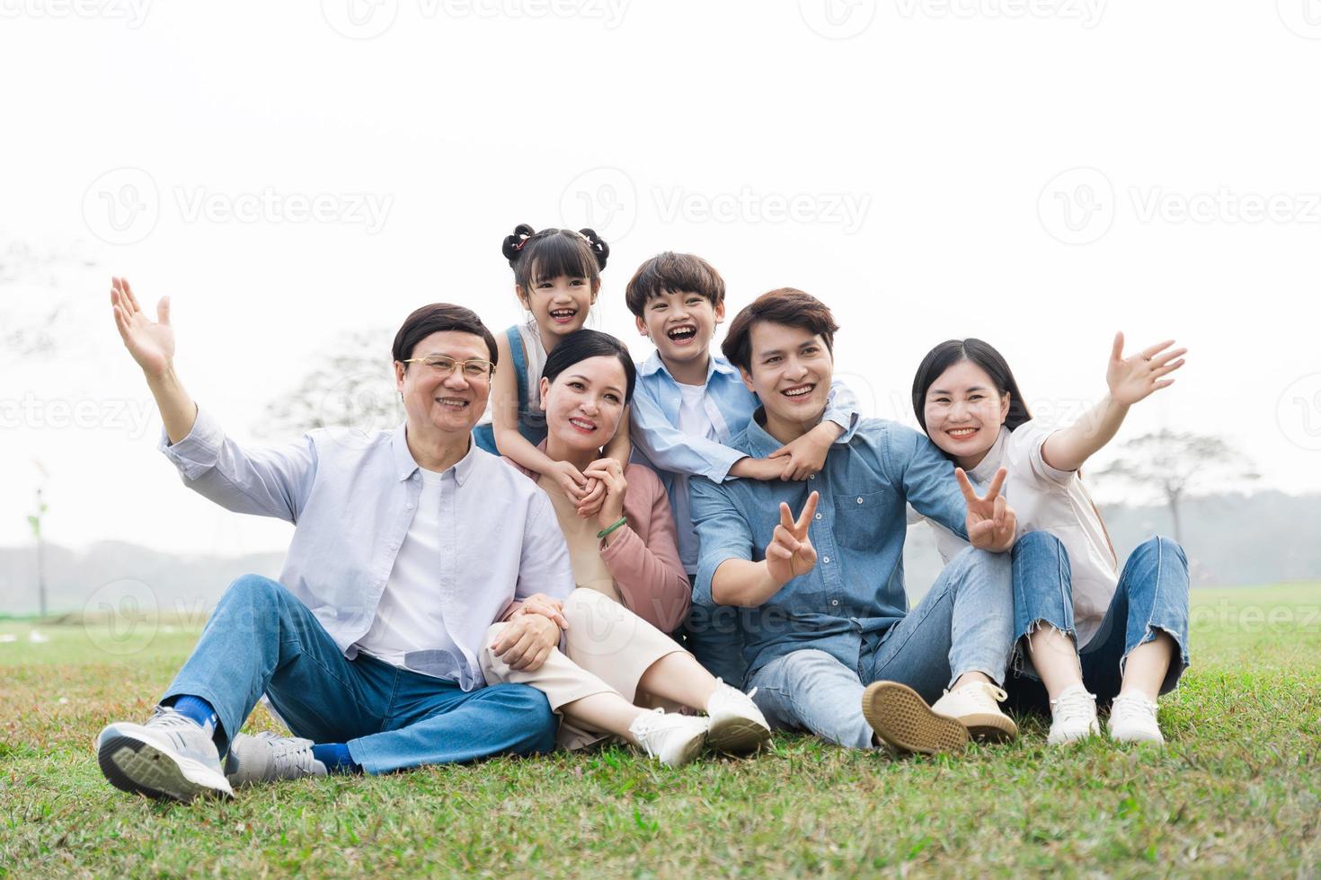 imagen de un asiático familia sentado juntos en el césped a el parque foto