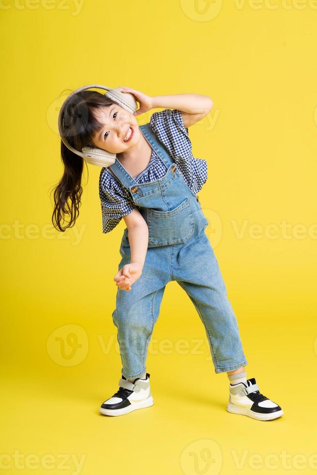 full body image of beautiful asian baby girl on yellow background photo