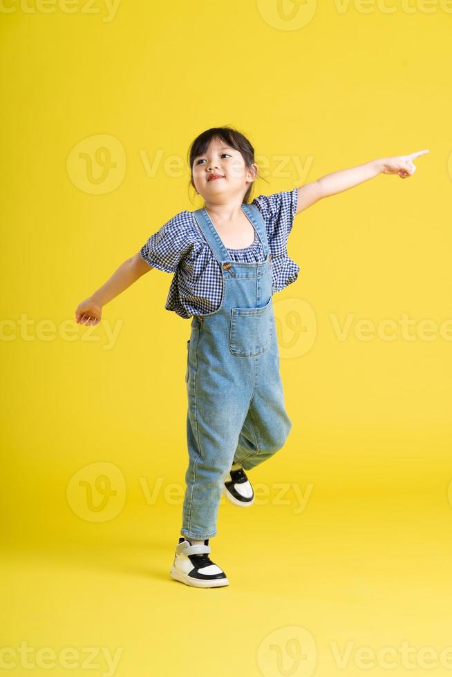 full body image of beautiful asian baby girl on yellow background photo