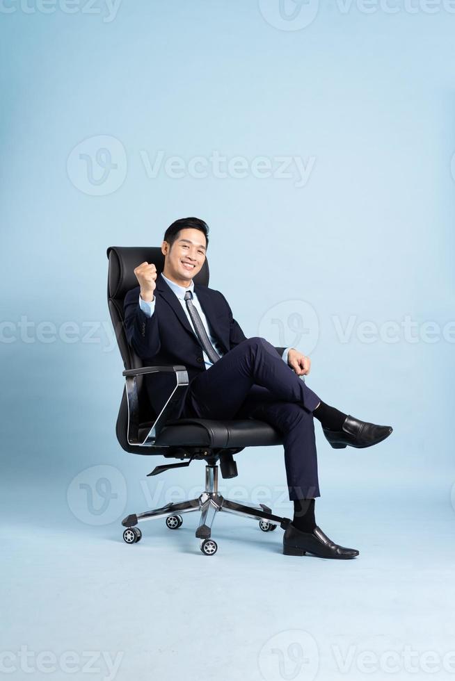 Asian businessman male portrait sitting on chair and isolated on blue background photo