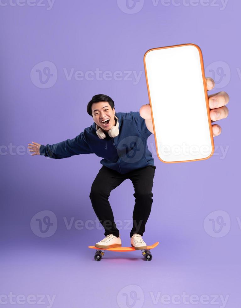 Image of young Asian man playing skateboard on purple background photo