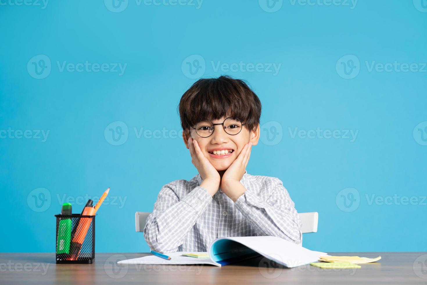 portrait of school boy sitting and studying on a blue background photo