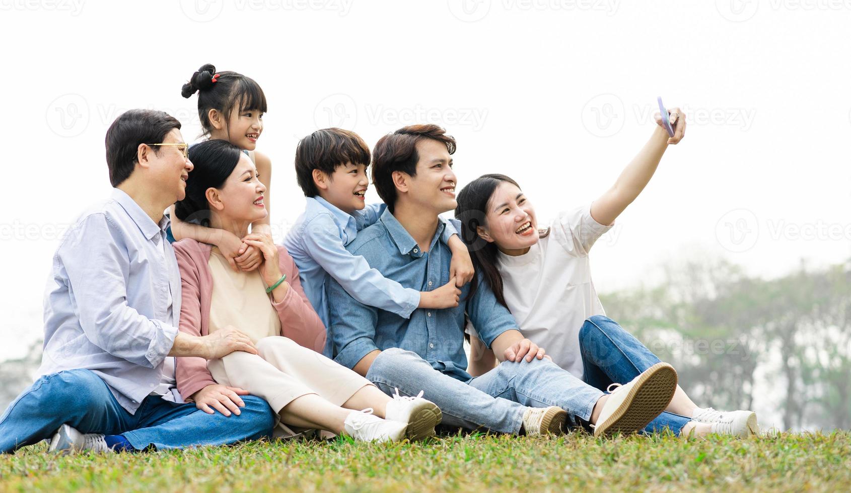 imagen de un asiático familia sentado juntos en el césped a el parque foto