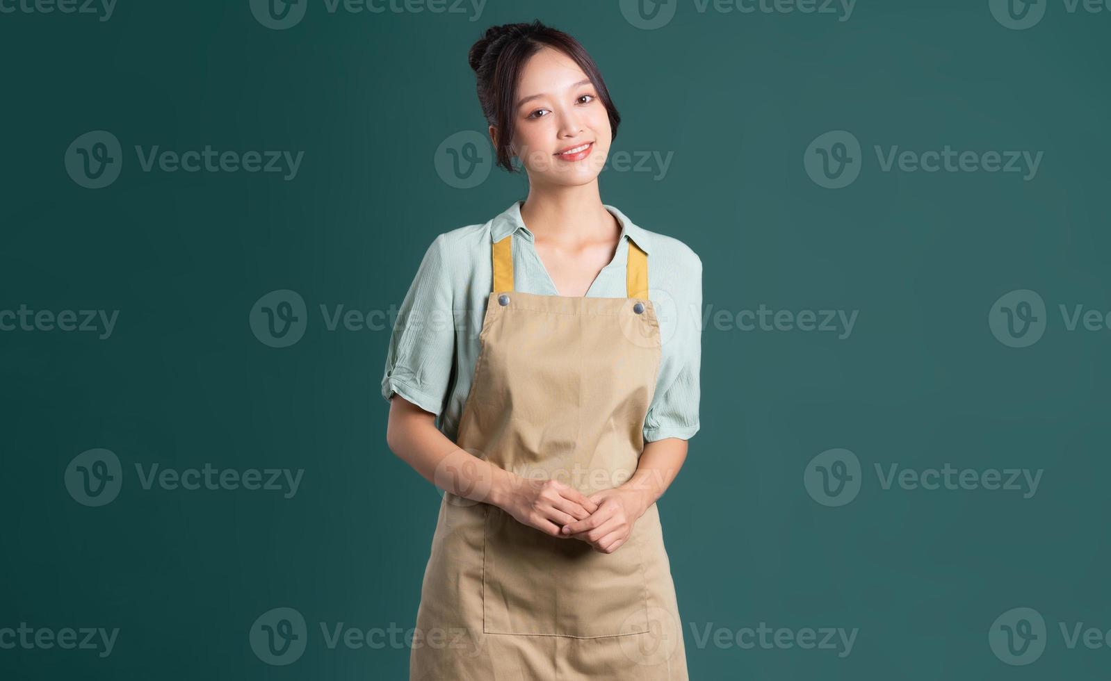 portrait of Asian woman wearing apron on green background photo