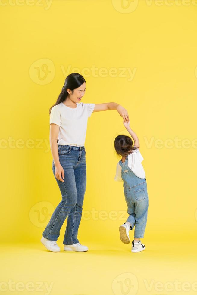 image of asian mother and daughter posing on a yellow background photo