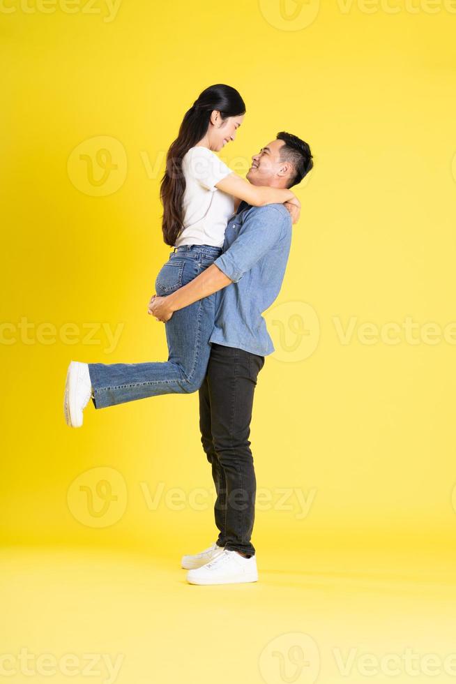 full body image of asian couple posing on yellow background photo