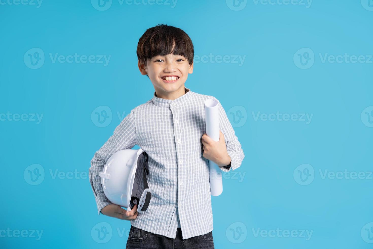 Asian boy portrait playing the role of an engineer, isolated on blue background photo