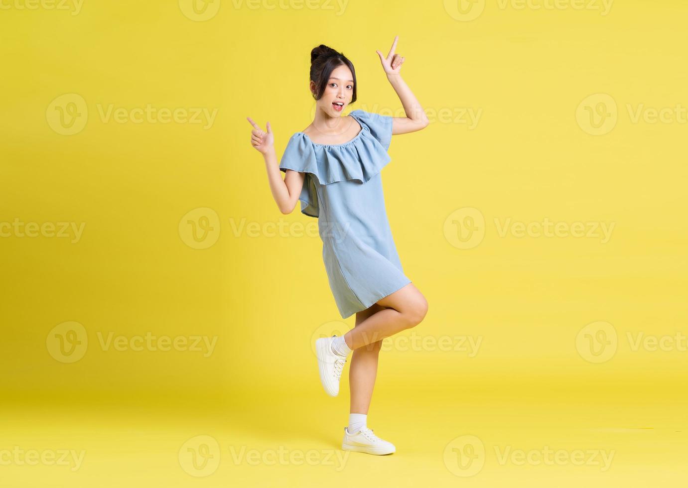 portrait of Asian woman in skirt posing on yellow background 21510899