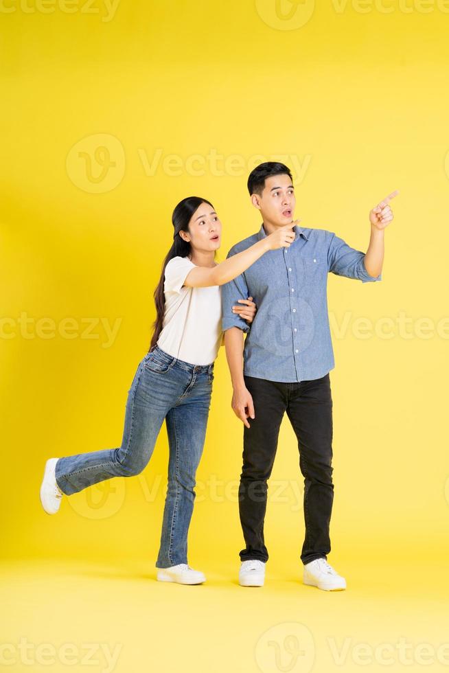 full body image of asian couple posing on yellow background photo