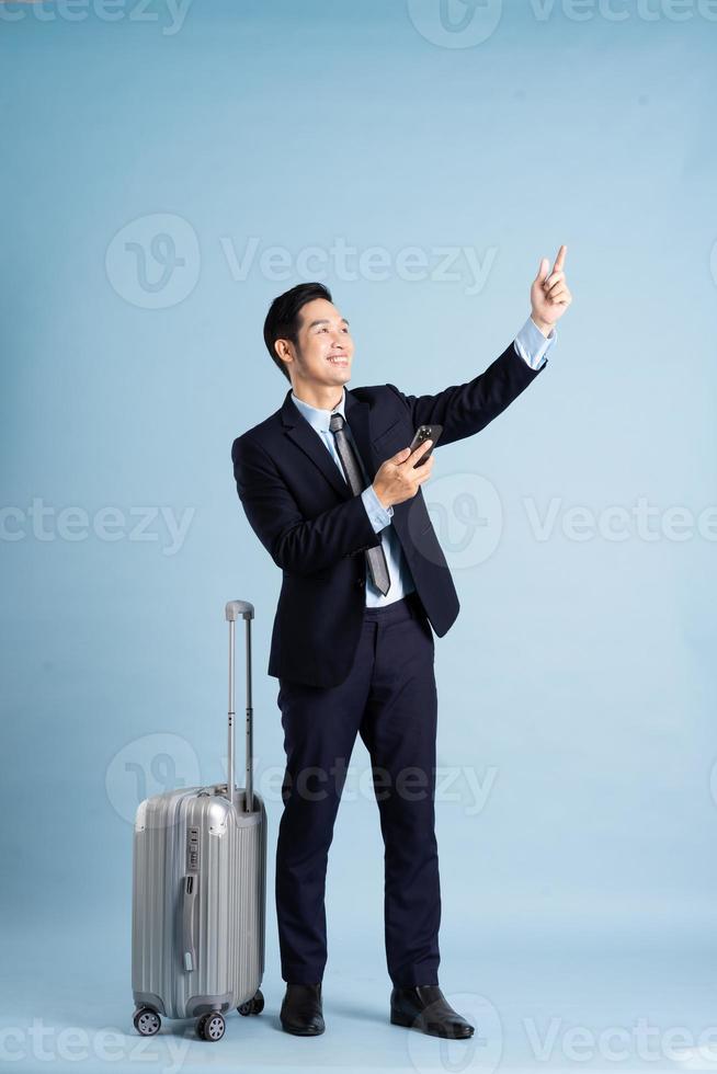 Portrait of Asian businessman wearing a suit and pulling a suitcase photo