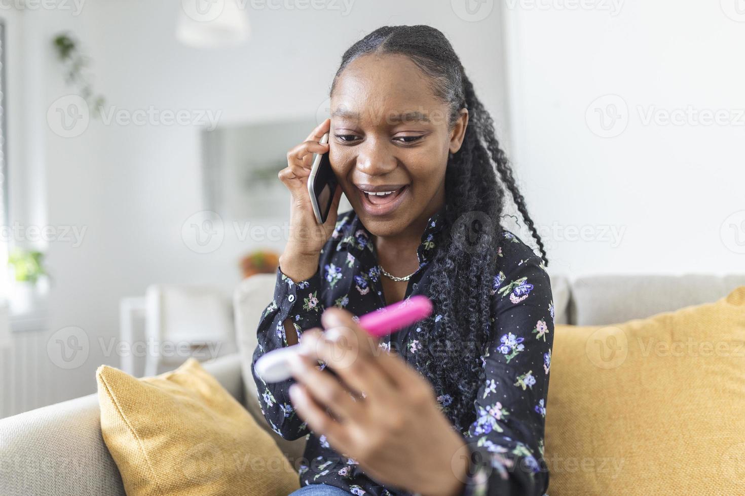 Finally pregnant. Young women looking at pregnancy test and smiling while calling the father to give him happy news. Young happy woman looking at a positive pregnancy test and calling husband by phone photo