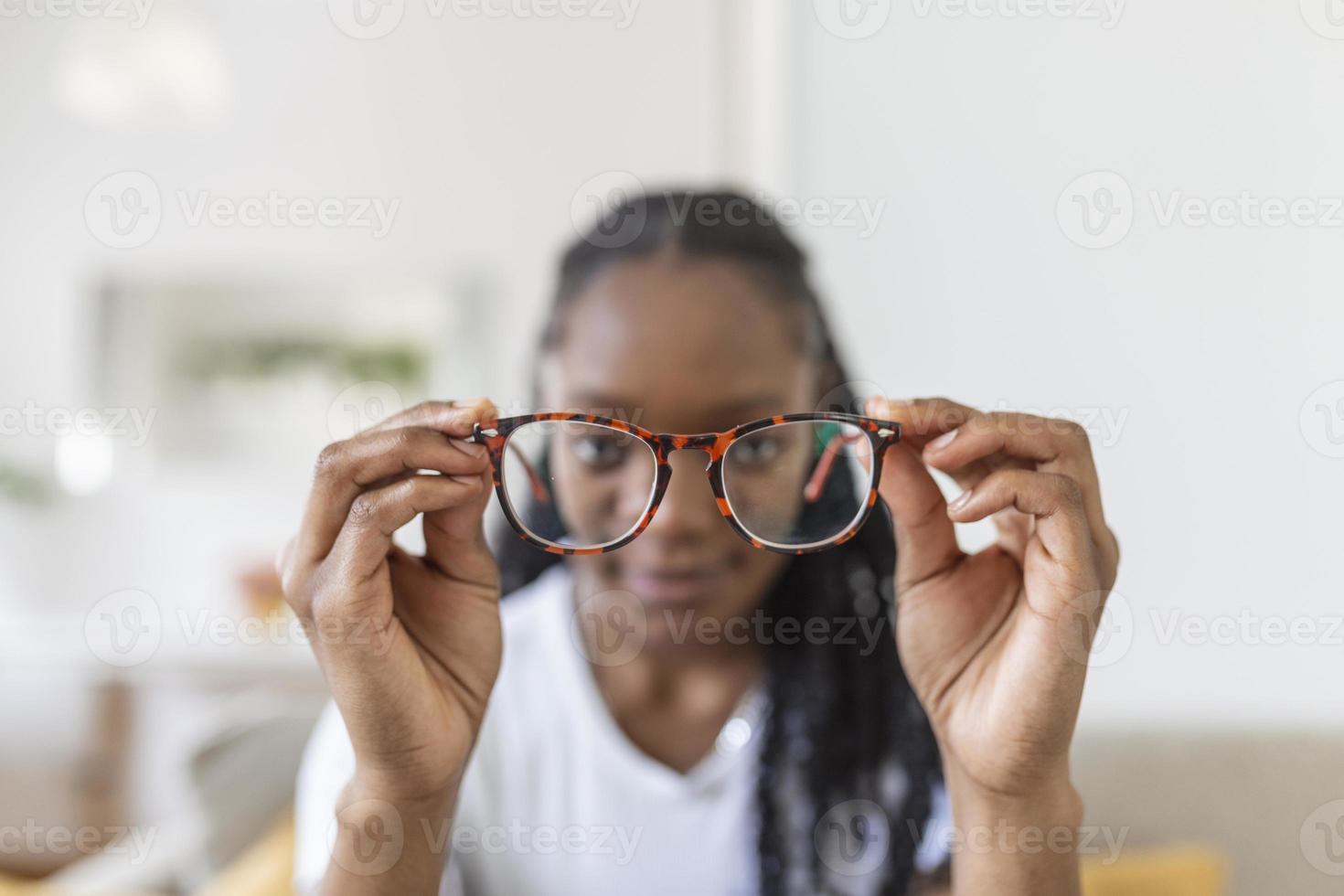 joven africano mujer sostiene lentes con dioptría lentes y mira mediante a ellos, el problema de miopía, visión corrección foto