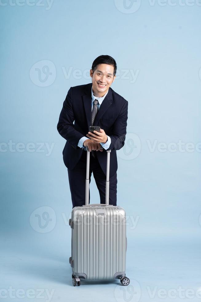 Portrait of Asian businessman wearing a suit and pulling a suitcase photo