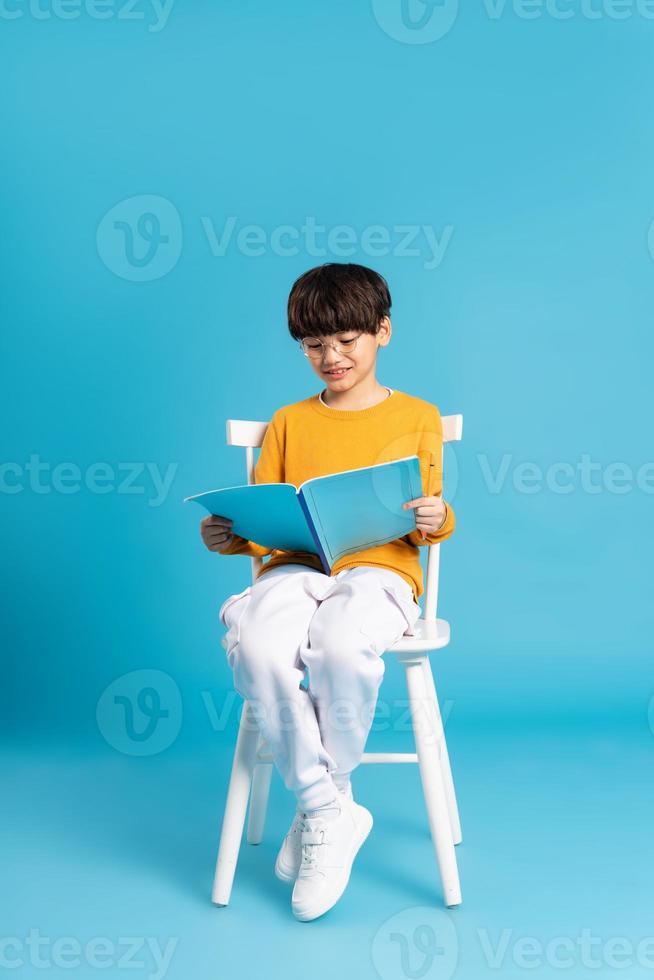 retrato de sentado chico, aislado en azul antecedentes foto